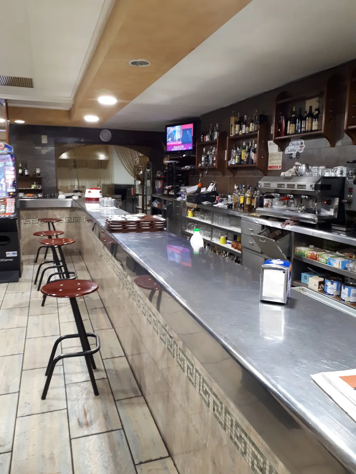 La barra de Casa Parra, larga y de acero, con taburetes y el frente de azulejo