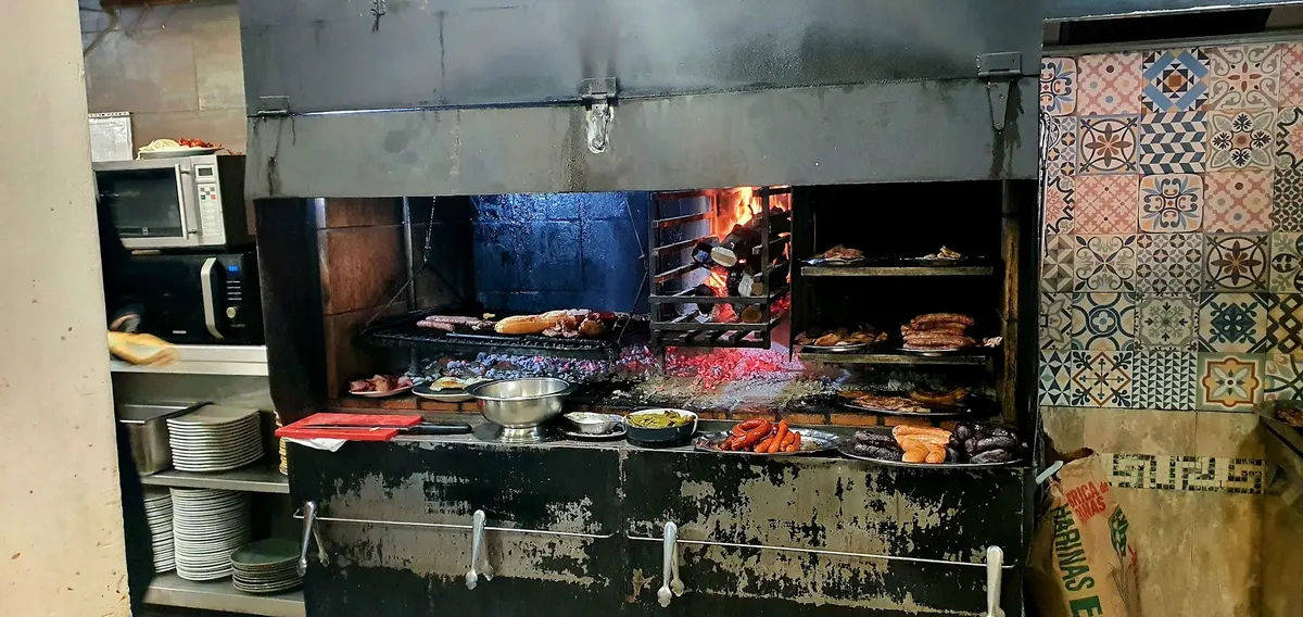 El asador de leña de la cocina, con la parrilla cargada y la pared de azulejos